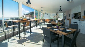 Une salle à manger spacieuse, dotée de hauts plafonds et de grandes fenêtres offrant une vue panoramique.