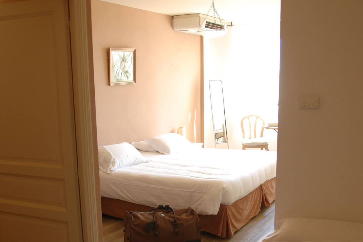 A bedroom with a bed, a chair, and a suitcase on the floor.