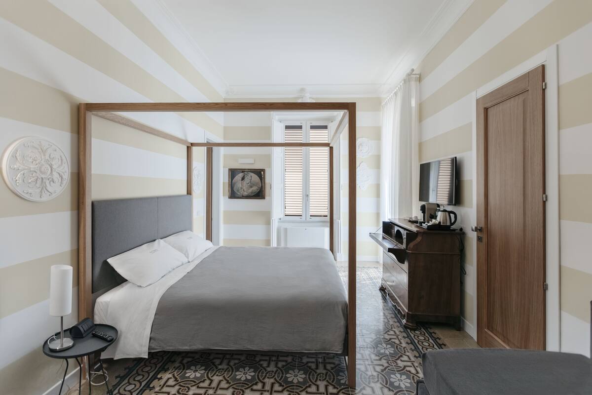 A hotel room with a bed, bedside table, lamp, and a television.