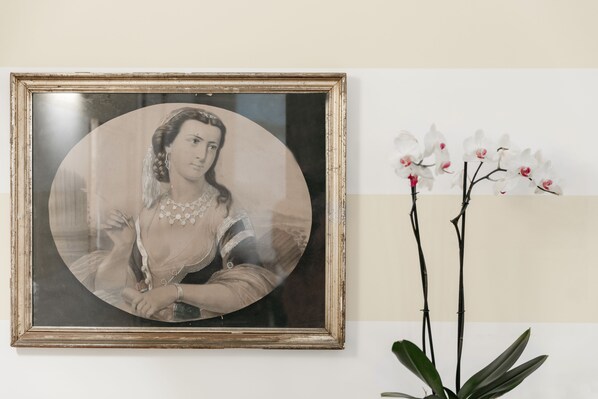 A framed portrait with a white orchid arrangement beside it.