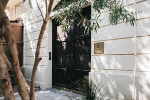 Un edificio con una puerta negra, una placa y una pared blanca.