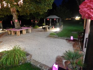 Un patio al aire libre con un pabellón, asientos y plantas en macetas.