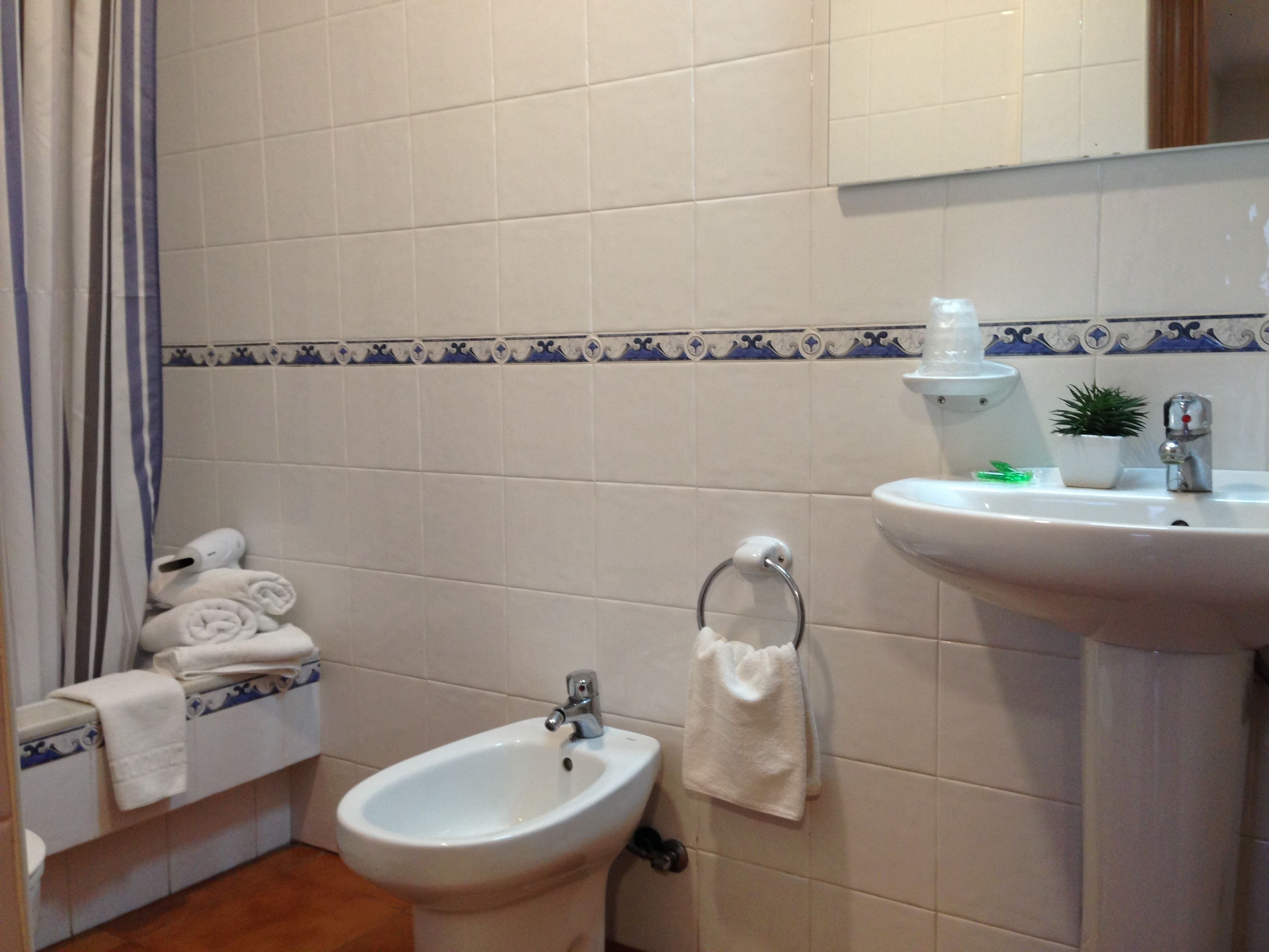 Un baño con bidé, lavamanos, espejo y toallero.