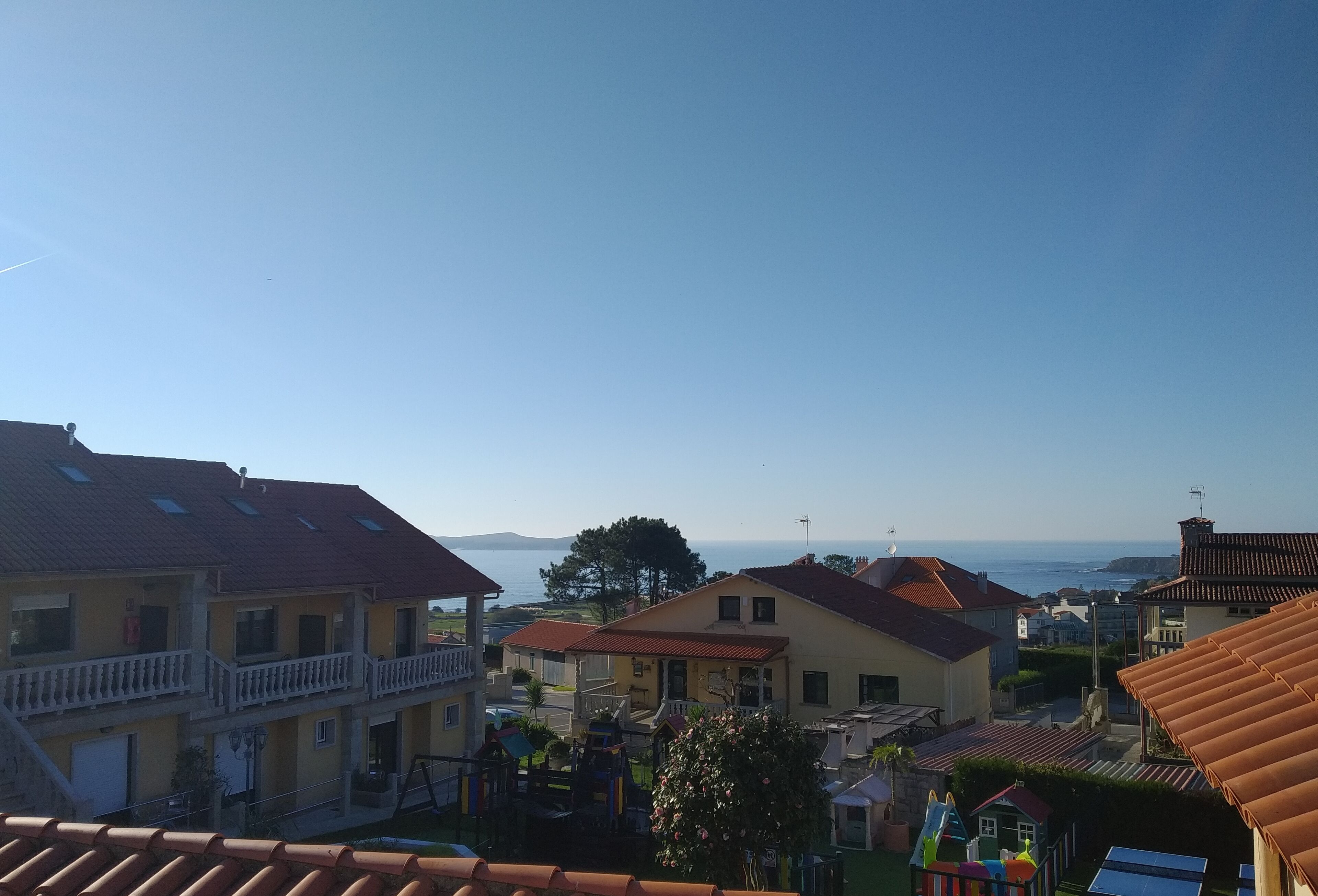 Ein Wohngebiet mit Häusern, einem Spielplatz und Blick auf das Meer.