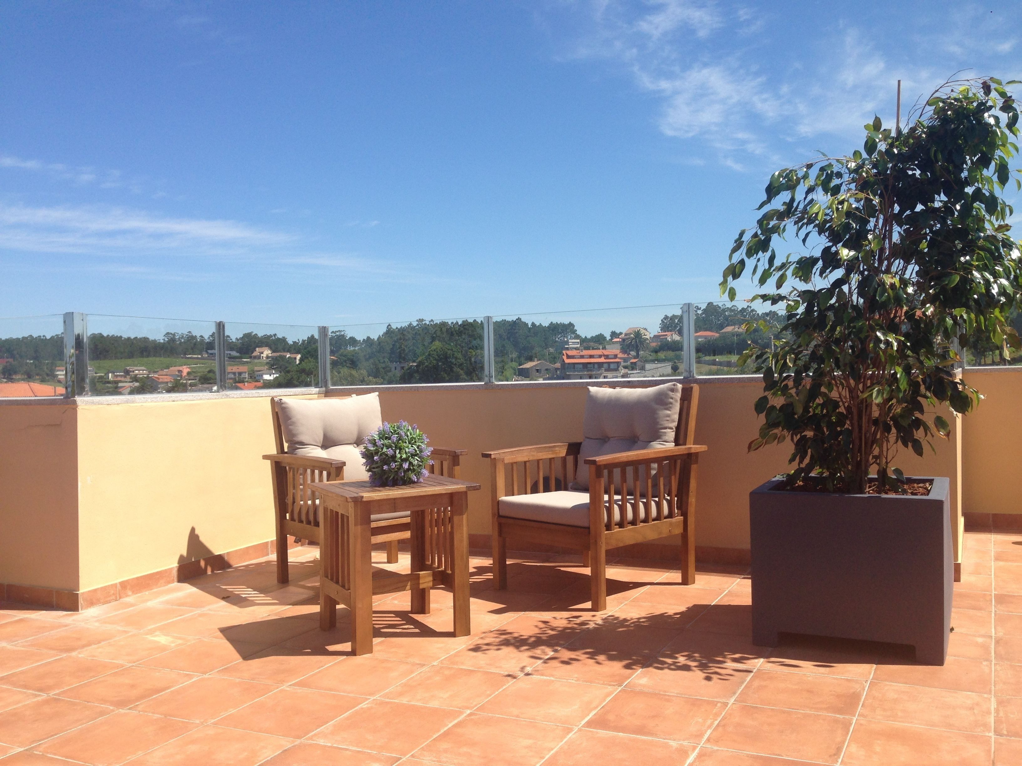 Una terrazza con due sedie di legno, un tavolino e una pianta in vaso.