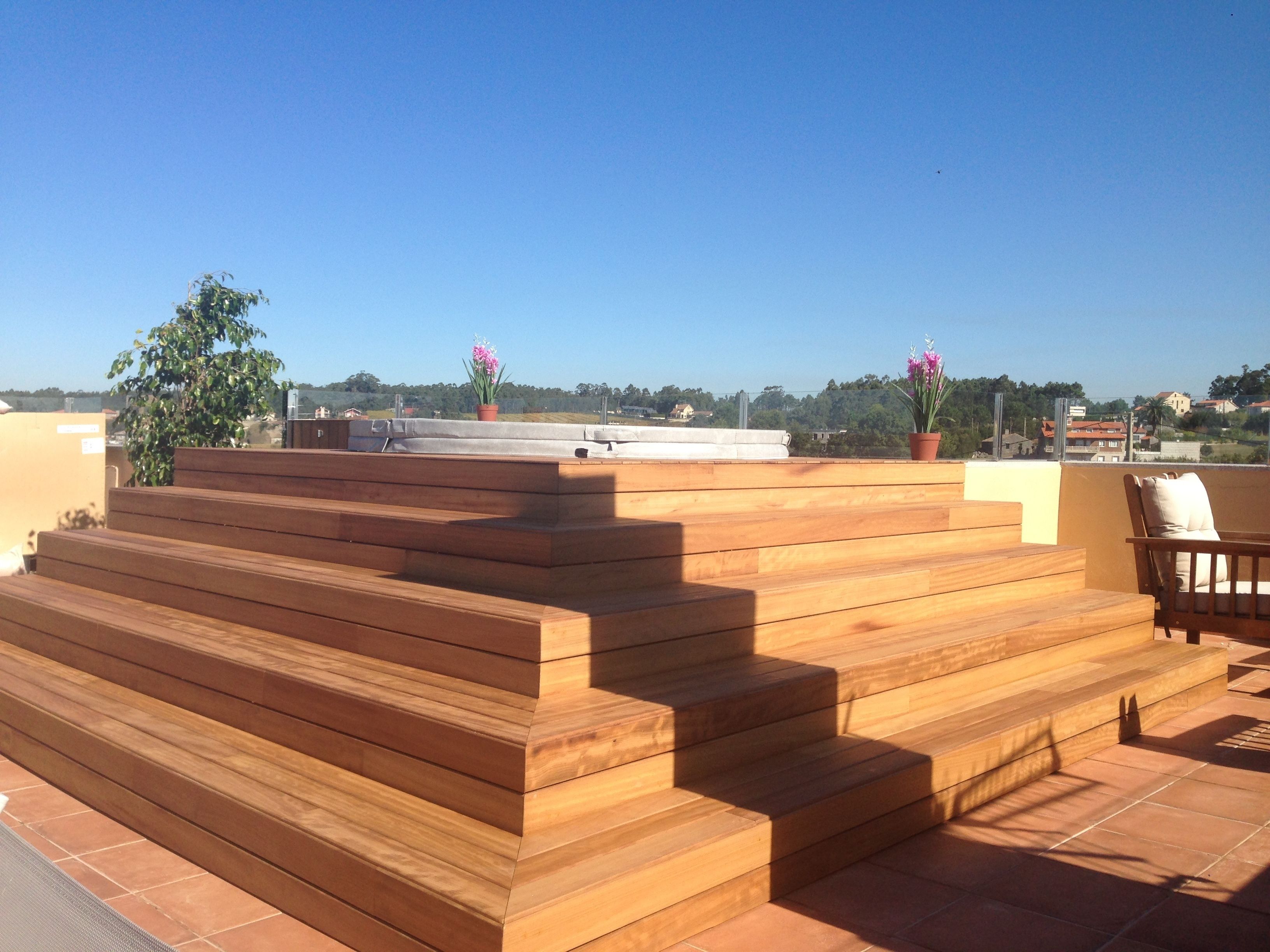 A wooden outdoor staircase leading to a terrace with a view of the surrounding landscape.