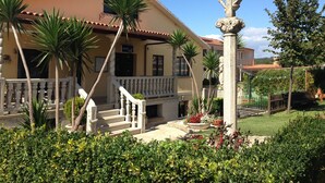 Ein Gebäude mit einem Balkon, einer Statue und einem Garten mit Palmen.