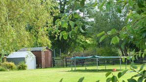 Une cour gazonnée avec un abri de jardin, une structure couverte et une clôture.