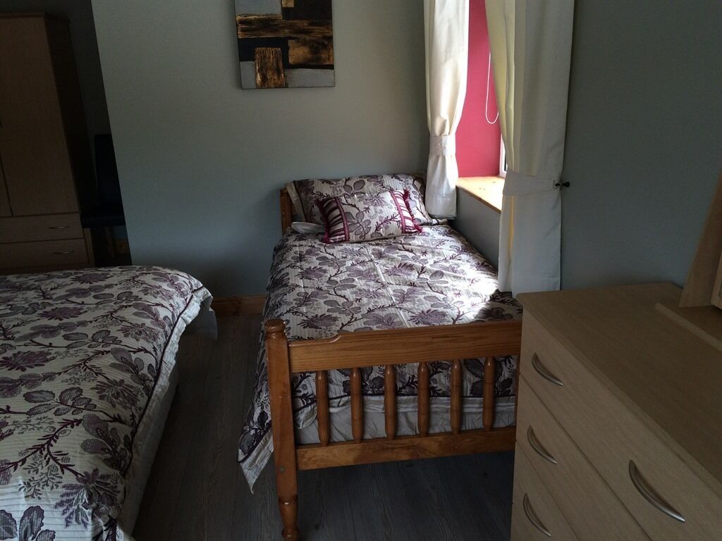 Un dormitorio con dos camas, un aparador y una ventana con cortinas.