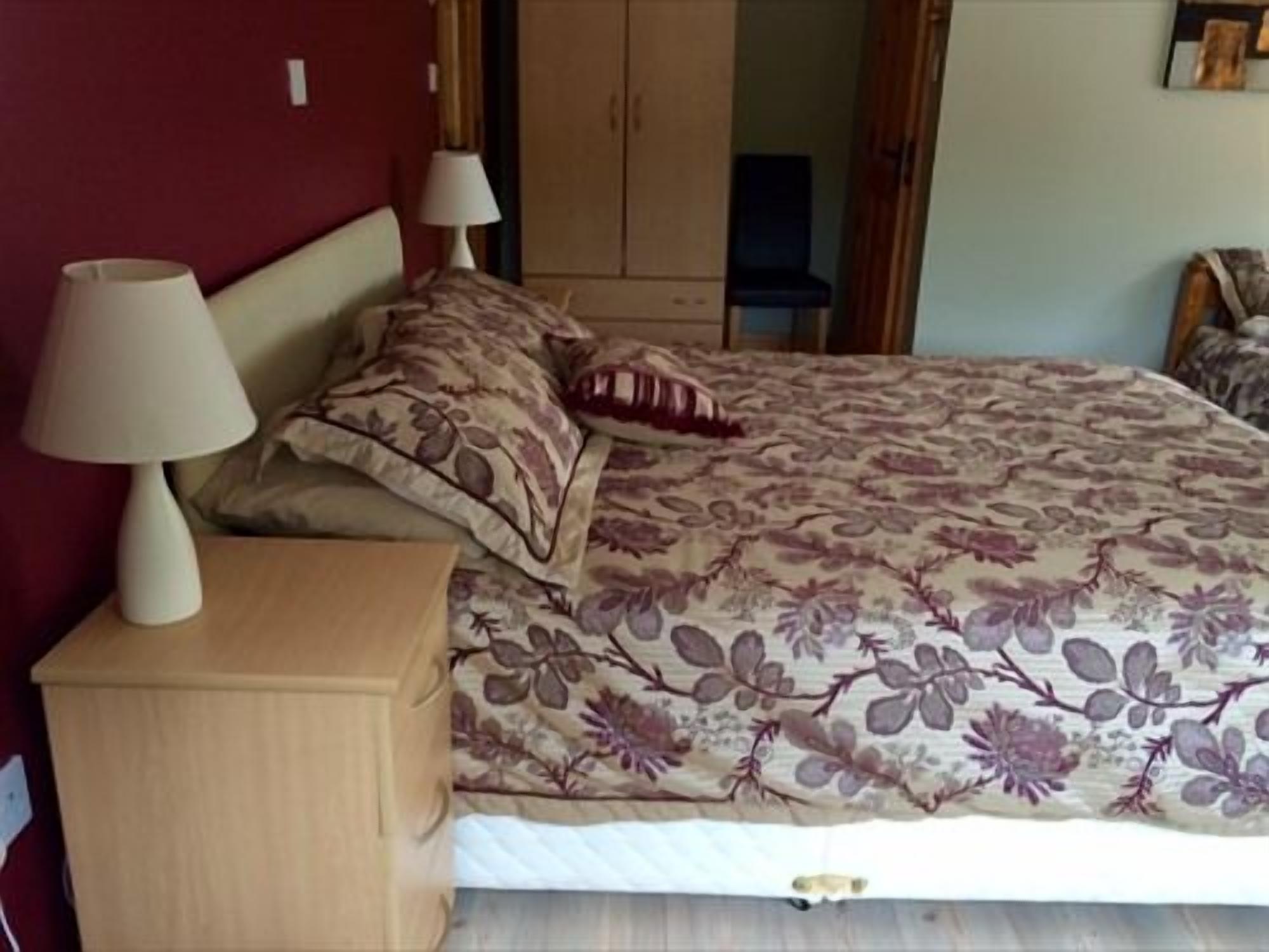 Un dormitorio con cama, mesitas de noche y un armario.