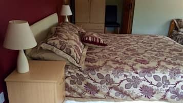Un dormitorio con cama, mesitas de noche y un armario.