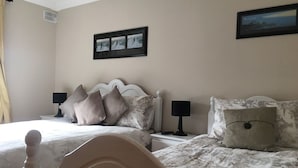 Une chambre à coucher avec deux lits, chacun doté d’une tête de lit, de tables de chevet, de lampes et d’un tableau encadré au mur.