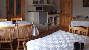 Une pièce confortable comprenant un lit, des chaises en bois, une table à manger et un coin cuisine avec des placards et un four à micro-ondes.
