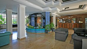 A spacious lobby with a central fountain, seating area, and a reception desk. - Prince Apart (Marmaris)