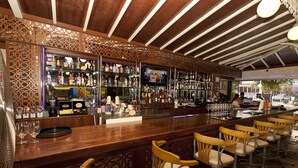 A bar area with wooden bar counters, bar stools, and shelves stocked with bottles. - Prince Apart (Marmaris)