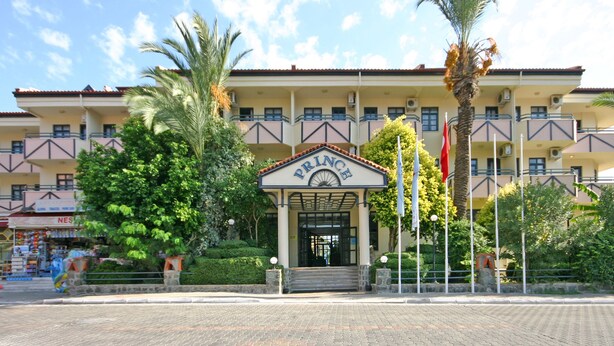 Un hotel con entrada principal, varios balcones y un jardín bien cuidado.