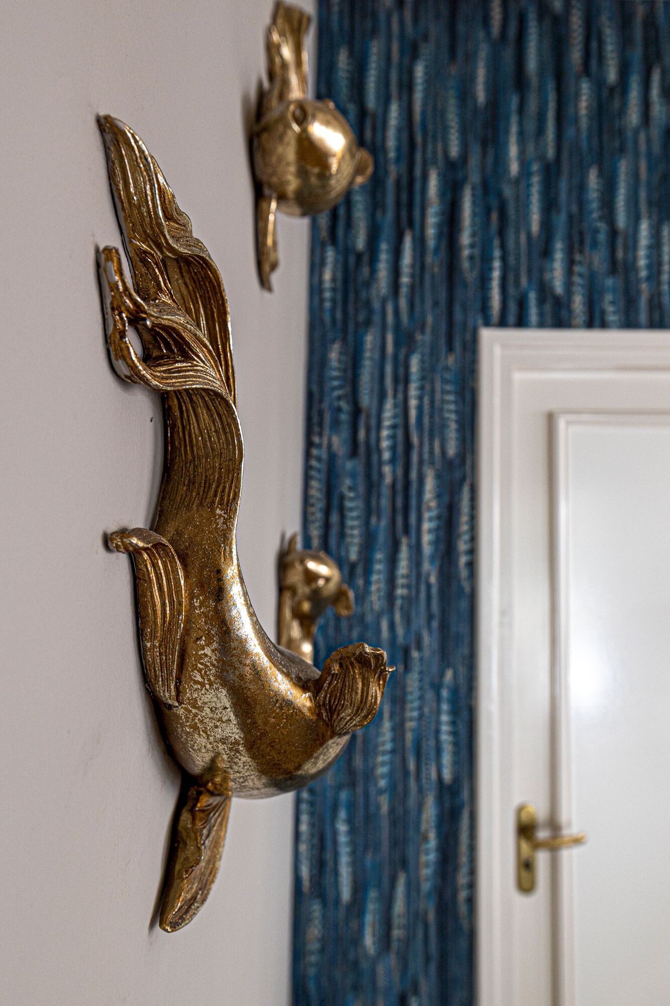 Une décoration murale représentant un poisson doré et une petite figurine d’oiseau doré.