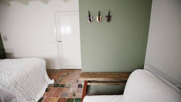 A room with two beds, a green wall, and a tiled floor.