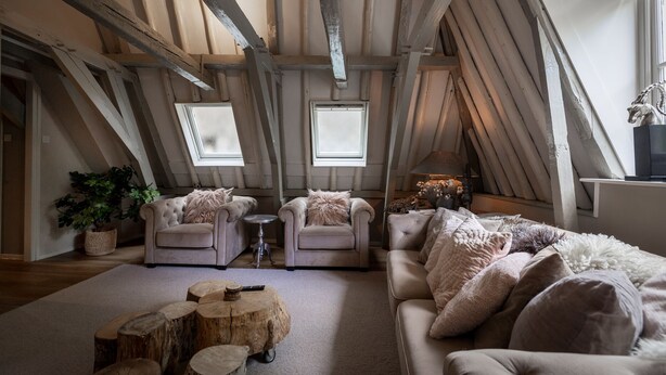 A loft-style room with exposed wooden beams, two windows, a sofa, armchairs, and a coffee table. - City House Grande Madame Agaath (Leeuwarden)