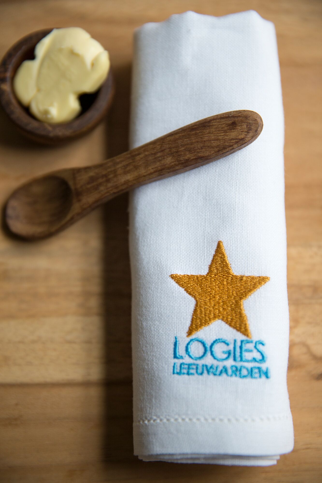 A white cloth with a golden star and embroidered text "LOGIES LEEUWARDEN" on it, placed on a wooden surface.