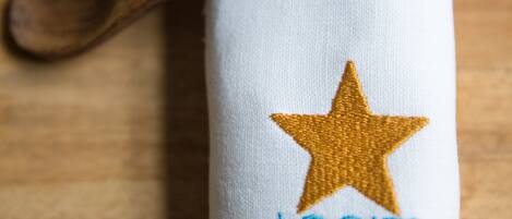 A white cloth with a golden star and embroidered text "LOGIES LEEUWARDEN" on it, placed on a wooden surface.