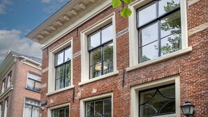 A two-story brick building with large windows and a black door. - City House Grande Madame Agaath (Leeuwarden)