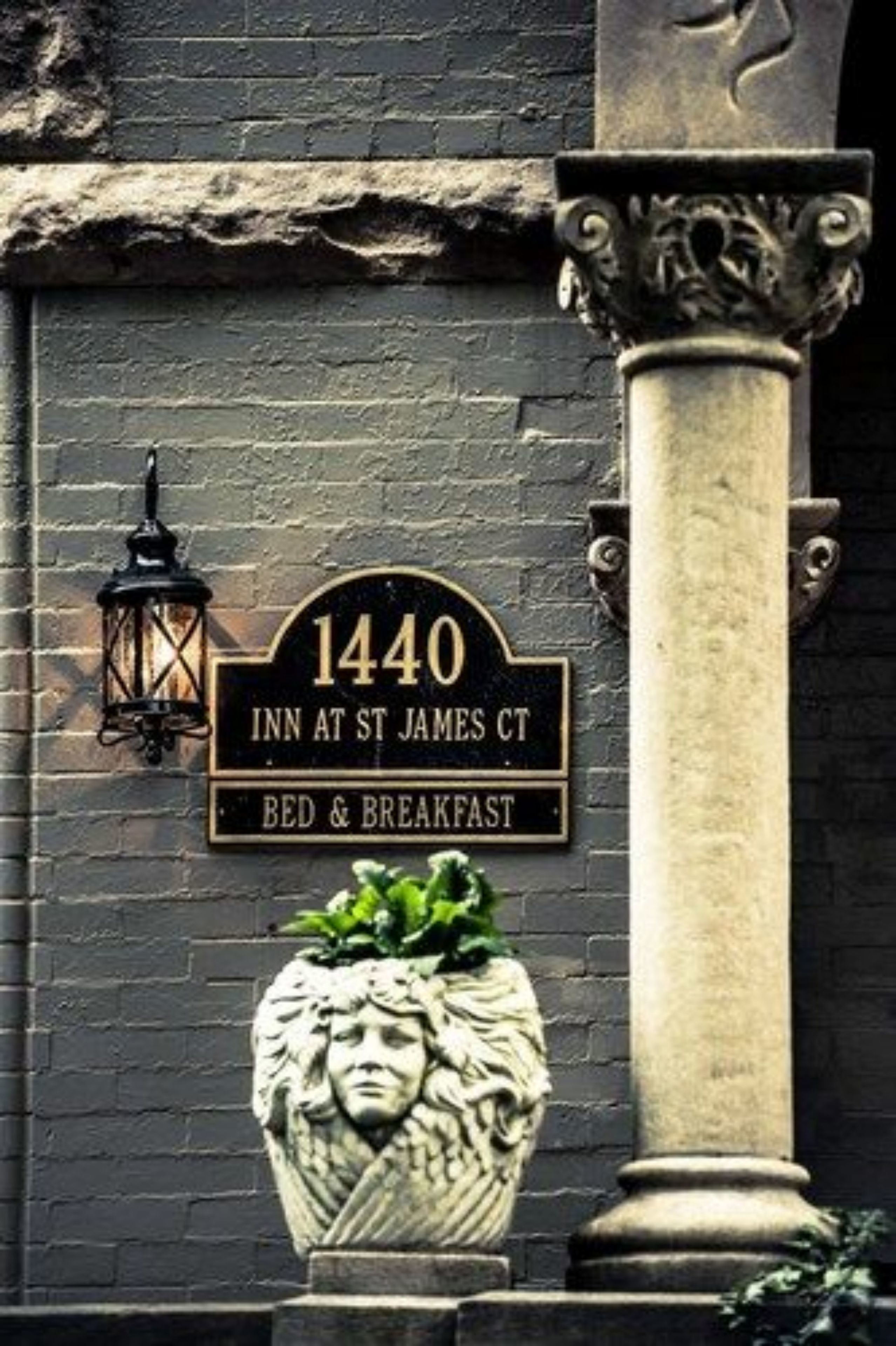 A black sign with gold lettering for '1440 Inn at St James Ct' offering bed and breakfast services.