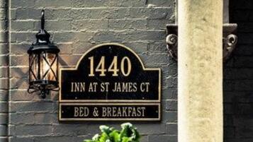 A black sign with gold lettering for '1440 Inn at St James Ct' offering bed and breakfast services.