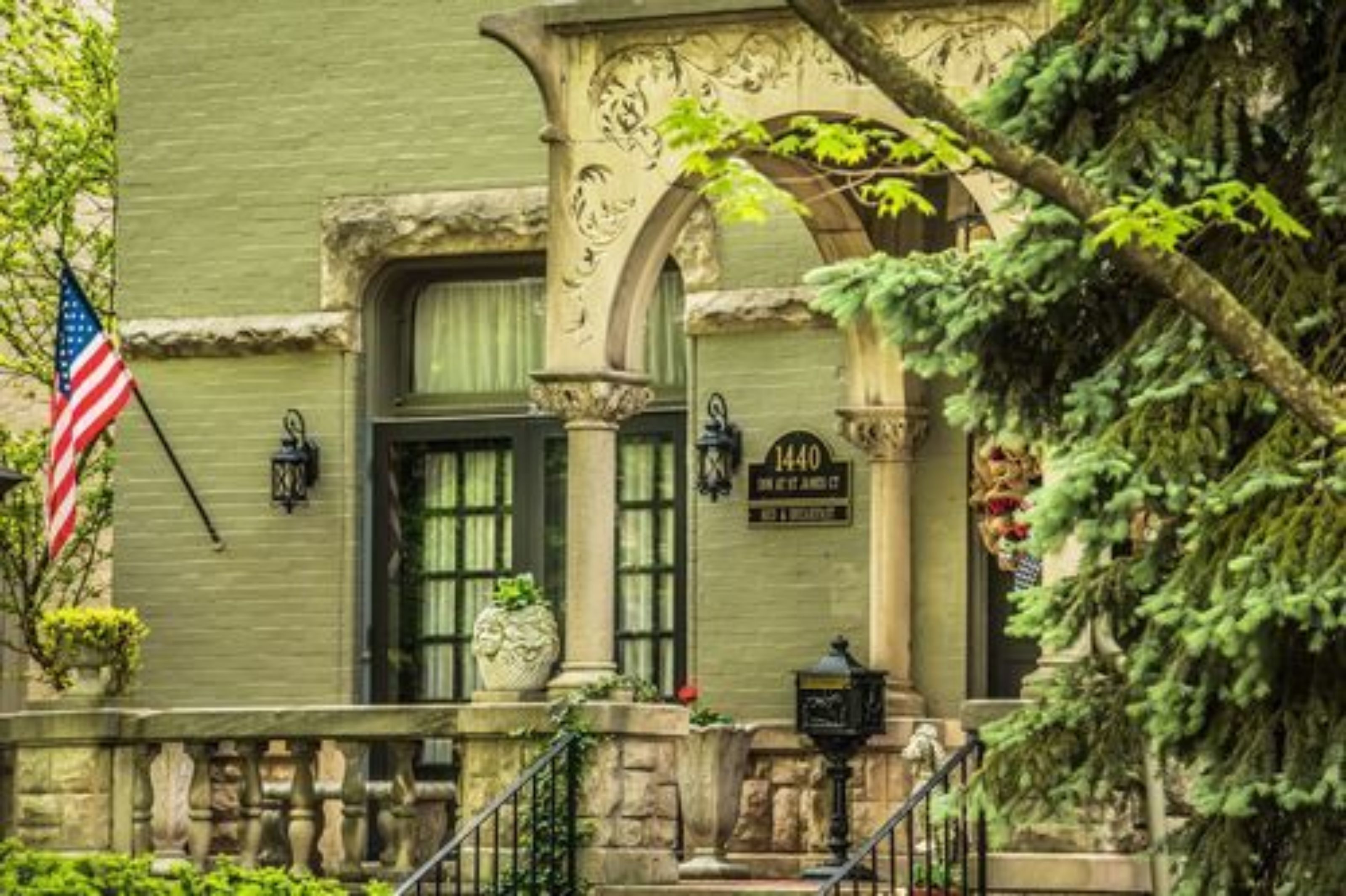 Un edificio histórico con fachada verde, entrada de piedra y una bandera.