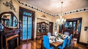 Un comedor con una mesa de madera, sillas azules, una araña y una chimenea.
