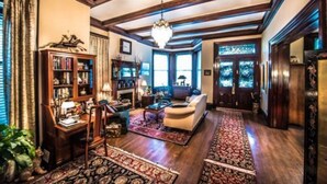Un salón amplio con chimenea, una araña y una gran estantería.