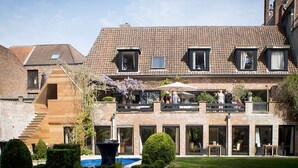 A two-story house with a brick facade, large windows, and a balcony with outdoor seating. - B&B Filemon & Baucis (Bruges)