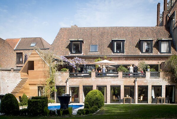 A two-story house with a brick facade, large windows, and a balcony with outdoor seating. - B&B Filemon & Baucis (Bruges)