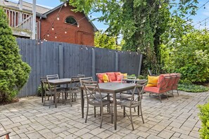 An outdoor patio with a table and chairs, a sofa, and a wooden fence. - Germantown Inn (Nashville)