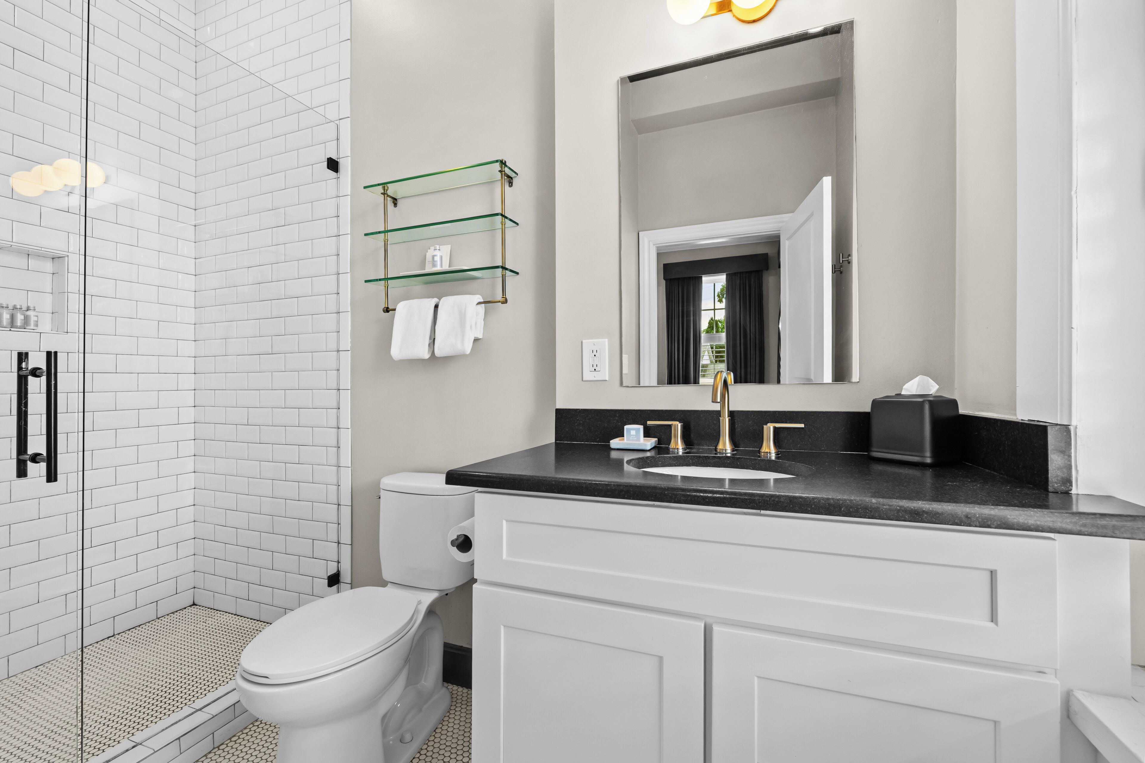 A modern bathroom with a glass shower enclosure, a toilet, a vanity with a sink, and a mirror.