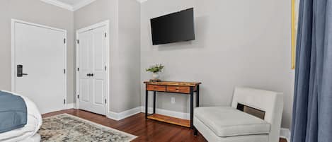 A room with a bed, a desk, a chair, a television, and a door.