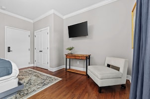A room with a bed, a desk, a chair, a television, and a door.