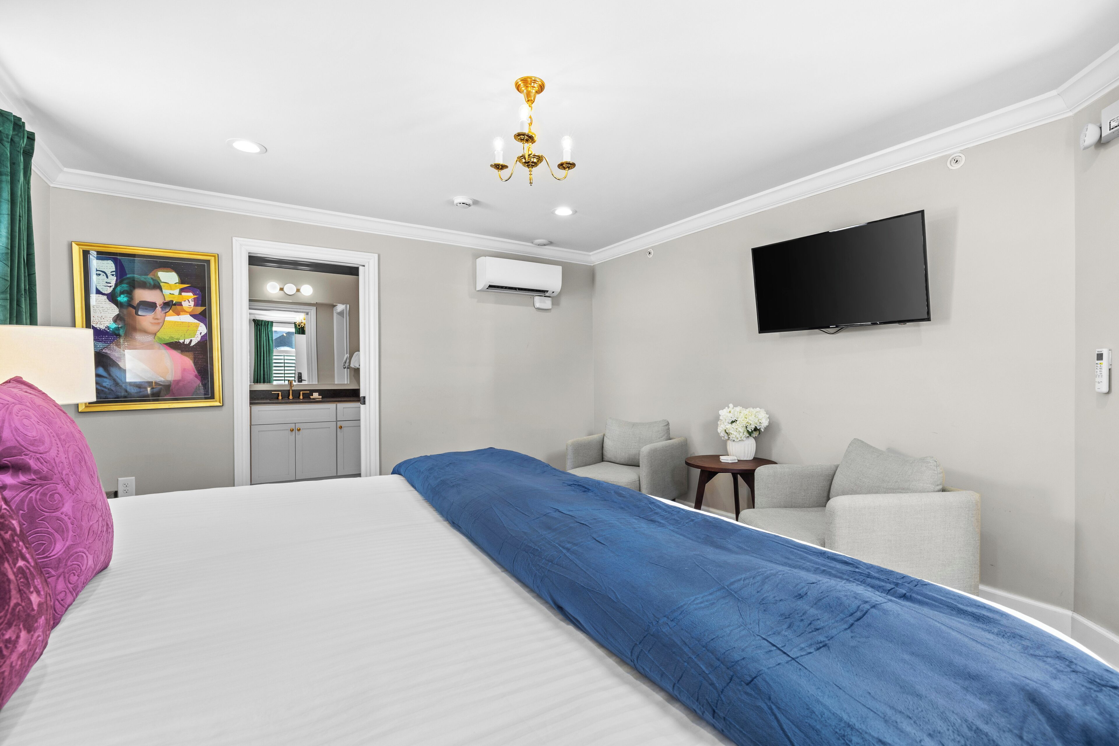 Une chambre d’hôtel avec un lit, une télévision, un canapé, une petite table et un miroir.