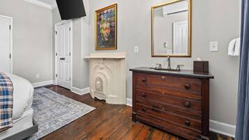 Un dormitorio con cama, cómoda, televisor, chimenea y espejo.