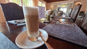 Una mesa dispuesta con un vaso alto de bebida, cubiertos y una carta.