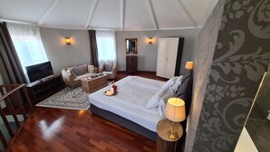 Un dormitorio amplio con una cama grande, un sofá, un televisor y una mesa de centro de madera.
