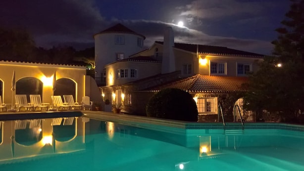 Una piscina con sillas de descanso y un edificio con torre.