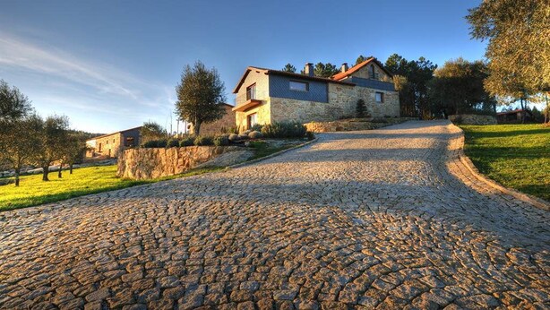 Una casa de pedra amb teulada inclinada i carrer d'accés pavimentat.