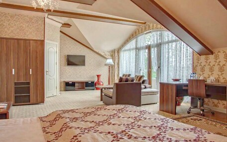 A bedroom with a large bed, a desk, a chair, a wardrobe, and a television.