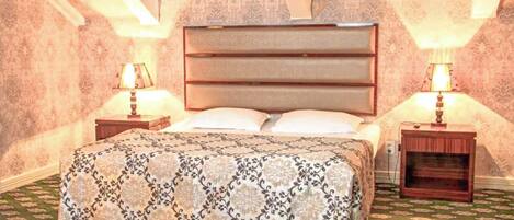 A bedroom with a bed, two bedside tables, and lamps.