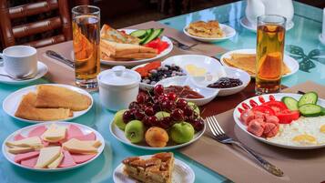 Mesa de café da manhã com diversos pratos, incluindo torradas, frutas, ovos e bebidas.