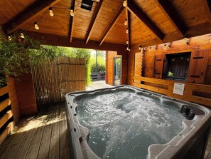 A hot tub in a wooden cabin with a bamboo fence and a wooden deck. - Gites D'armor (Treguidel)