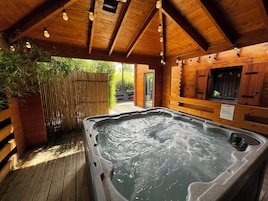 Un jacuzzi en una cabaña de madera con una cerca de bambú y una terraza de madera.