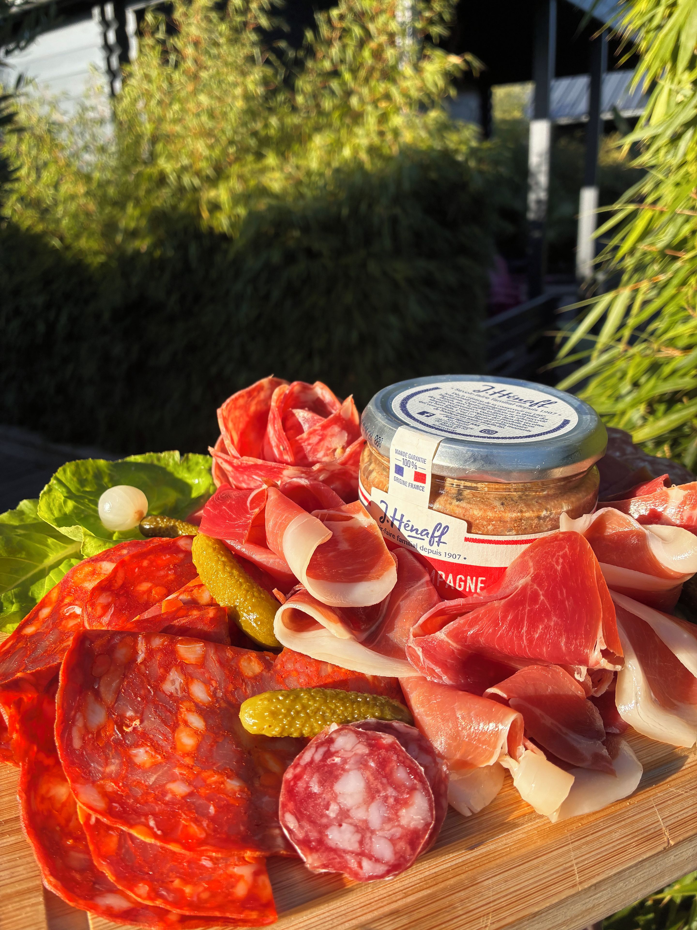 A variety of cured meats and pickles on a wooden board.
