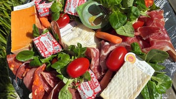 Una tabla de quesos y embutidos con diversas carnes, quesos y verduras.